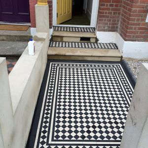 process of laying victorian black and white floor tiles in front of a house